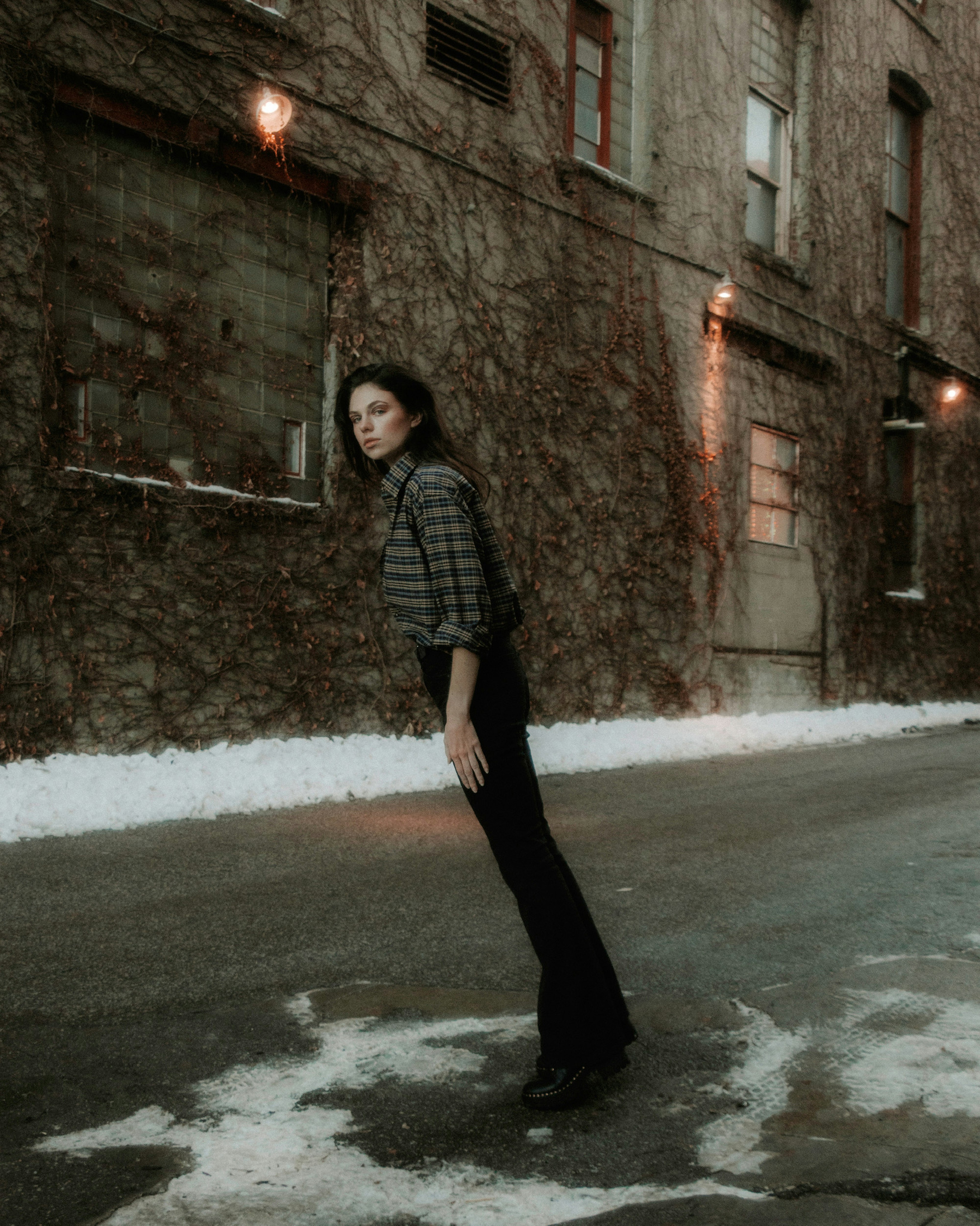 woman in black and white striped long sleeve shirt and black pants standing on gray concrete